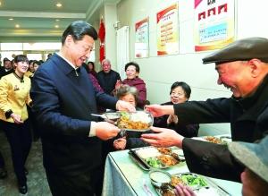 2月4日，在兰州一家“虚拟养老院”的养老餐厅，习近平端起一个盛满饭菜的餐盘，走到72岁的老人杨林太面前，轻轻送上，请他用餐。 新华社发