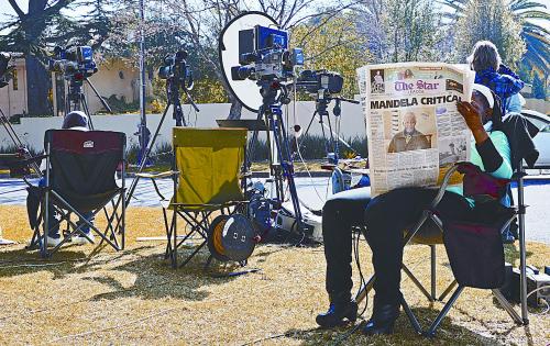 24日，记者们守在曼德拉所住医院外等候消息。