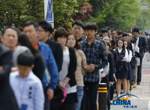 4月26日，在韩国安山一处临时客轮遇难者纪念堂附近，民众排起长队前来悼念这些逝去的人。（图片来源：英国媒体） 