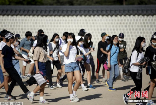 6月3日，在韩国首尔市中心的商业区，游客戴口罩出行。