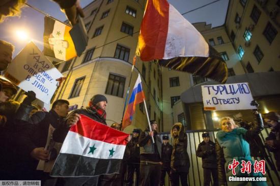 抗议者手持叙利亚与俄罗斯的国旗，在当地土耳其大使馆外抗议。据悉，俄罗斯一架苏－24战斗机11月24日在土耳其和叙利亚边境叙利亚一侧坠毁。