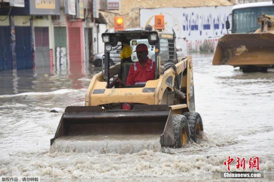 当地时间2016年4月13日，沙特首都利雅得，暴雨致街道被淹，市政工人清理积水。受天气影响，沙特许多学校停课。