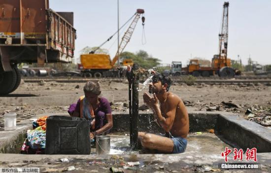 4月7日消息，进入4月份之后，印度多个地方气温迅速攀升，突破40摄氏度。根据官方7日统计，持续约一周的热浪已造成至少66人丧生。图为印度艾哈迈达巴德，当地民众在一条铁路旁边的水阀下洗澡洗衣服。