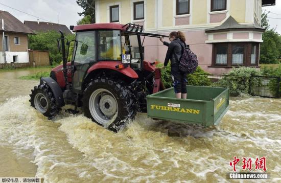德国累根河水也蔓延到附近的小镇上，图为一辆农用拖拉机开上积满水的街道。