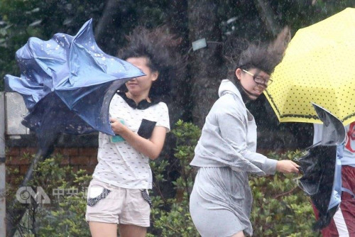 走在台北街头的民众撑伞，仍抵挡不住强风的吹袭。台湾”中央社”记者吴翊宁 摄