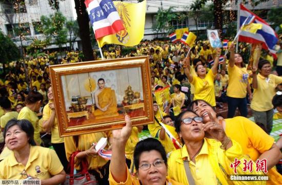 泰国民众手持国王图像游行为普密蓬国王庆生祈福。