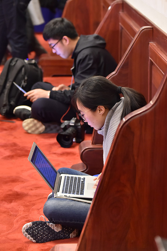 3月4日，女记者席地而坐争分夺秒的在编写稿件。