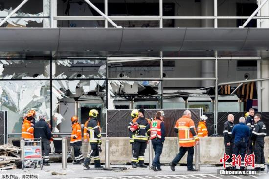 资料图：比利时布鲁塞尔遭到爆炸袭击的机场，爆炸后工作人员清理玻璃碎片。