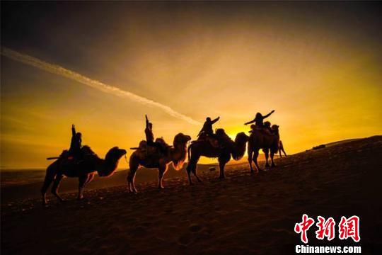 初春时节，游客在鸣沙山观赏敦煌大漠日出。　资料图 王斌银 　摄