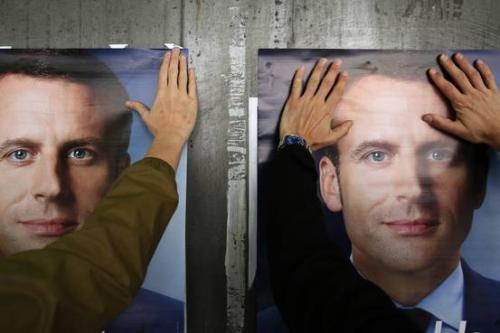 法国总统候选人马克龙的支持者在张贴竞选海报。