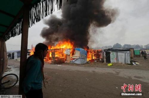 资料图：当地时间2016年10月26日，法国加莱“丛林”难民营被拆除，难民营内的帐篷和棚屋被点着起火，黑烟滚滚。