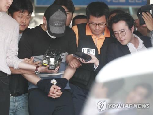 6月15日上午，在首尔市西大门警察署，炸伤导师的学生金某（戴帽子和口罩）前往法院接受羁押必要性审查。（图片来源：韩联社）