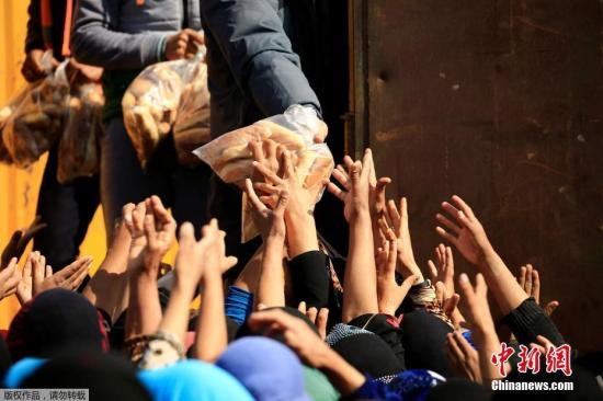 资料图：当地时间2017年3月14日，伊拉克摩苏尔，Hammam al-Alil难民营的难民，难民争抢救济面包。
