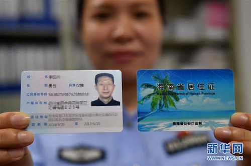 2016年5月20日，海南省海口市海垦派出所的民警展示首张发放的居住证。新华社记者 郭程 摄