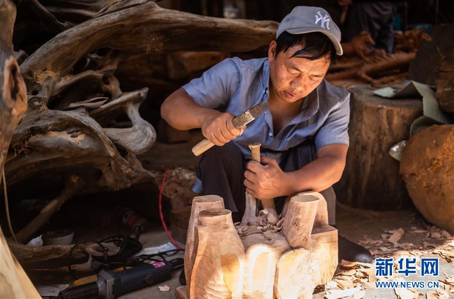 5月18日,残疾员工张军在木雕工艺厂内进行木雕创作.